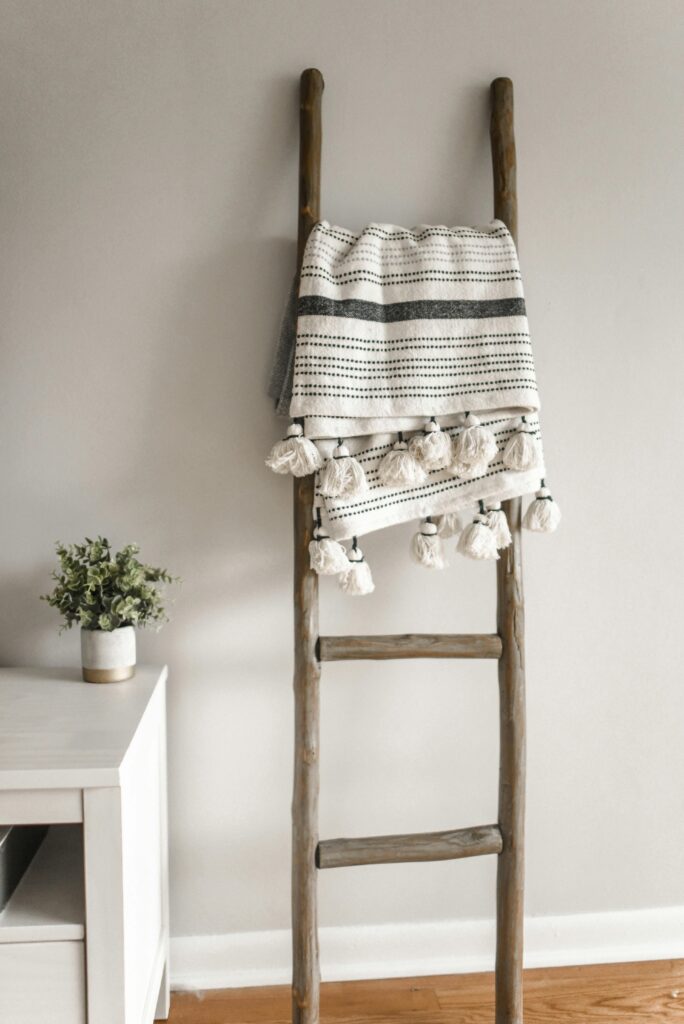 A modern decorative ladder with a hanging blanket in a cozy home setting.